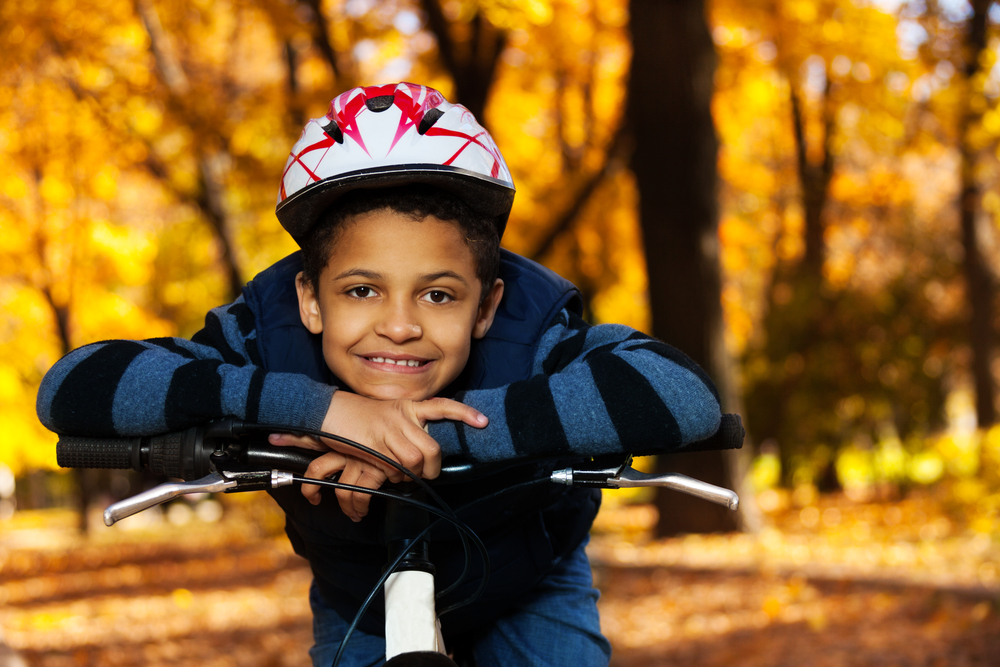 Мальчик сидит на велосипеде. Фото мальчик едет на велосипеде в парке а шлеме. Мальчик на низком трехколесном Велике черно белое фото. Photomontage a boy in a Helmet with Ears.